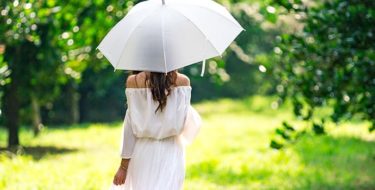 Een vrouw die tijdens warm weer met een parasol loopt omdat ze last heeft van jeukende huid